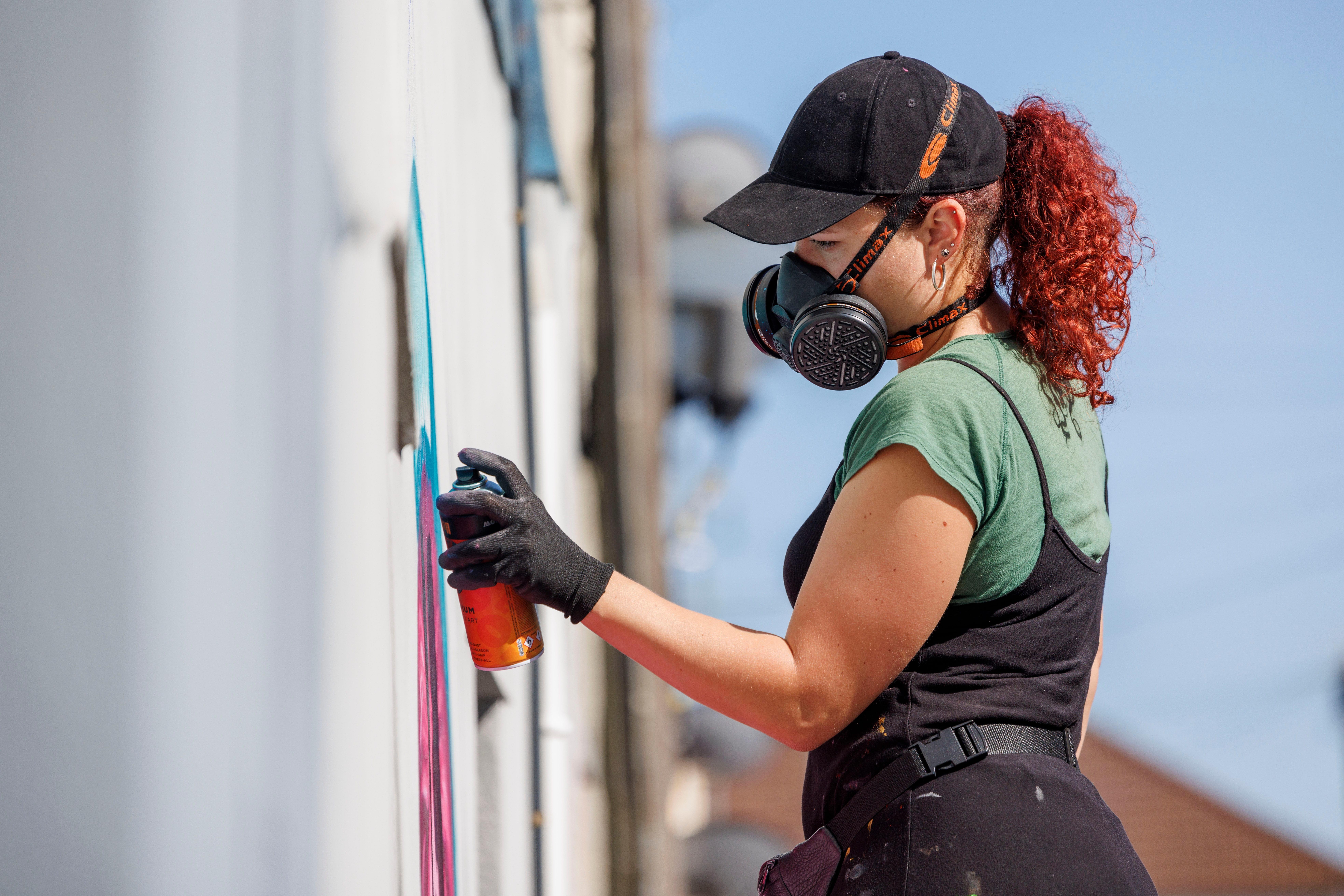 Lady spray painting a wall